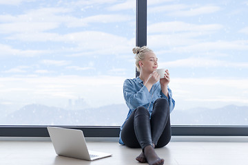 Image showing woman drinking coffee and using laptop at home