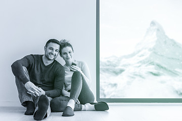 Image showing young couple sitting on the floor near window at home