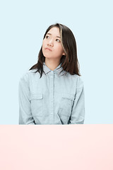 Image showing The serious business woman sitting and looking up against blue background.