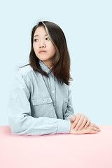 Image showing The serious business woman sitting and looking at left against blue background.