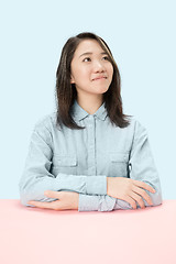 Image showing The serious business woman sitting and looking up against blue background.