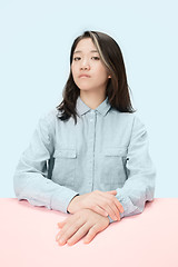 Image showing The serious business woman sitting and looking at camera against blue background.