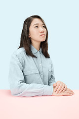 Image showing The serious business woman sitting and looking up against blue background.