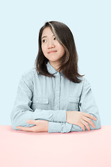 Image showing The serious business woman sitting and looking at left against blue background.