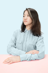 Image showing The serious business woman sitting and looking at left against blue background.