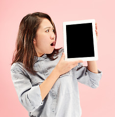 Image showing Portrait of a confident casual girl showing blank screen of laptop isolated over pink background