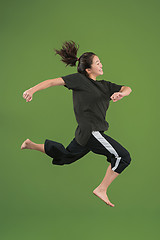 Image showing Freedom in moving. Pretty young woman jumping against green background