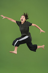 Image showing Freedom in moving. Pretty young woman jumping against green background