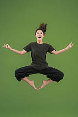 Image showing Freedom in moving. Pretty young woman jumping against green background