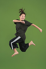 Image showing Freedom in moving. Pretty young woman jumping against green background