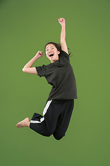 Image showing Freedom in moving. Pretty young woman jumping against green background