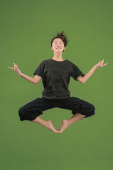 Image showing Freedom in moving. Pretty young woman jumping against green background