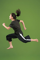 Image showing Freedom in moving. Pretty young woman jumping against green background