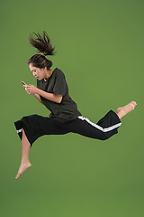 Image showing Freedom in moving. Pretty young woman jumping against green background