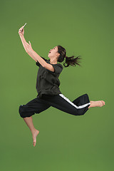 Image showing Freedom in moving. Pretty young woman jumping against green background