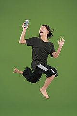 Image showing Freedom in moving. Pretty young woman jumping against green background