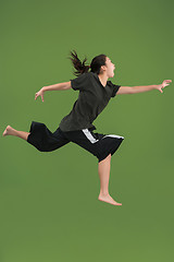 Image showing Freedom in moving. Pretty young woman jumping against green background