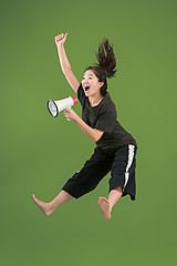 Image showing Beautiful young woman jumping with megaphone isolated over green background