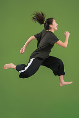 Image showing Freedom in moving. Pretty young woman jumping against green background