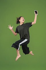 Image showing Freedom in moving. Pretty young woman jumping against green background