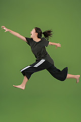 Image showing Freedom in moving. Pretty young woman jumping against green background