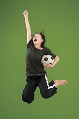 Image showing Forward to the victory.The young woman as soccer football player jumping and kicking the ball at studio on green