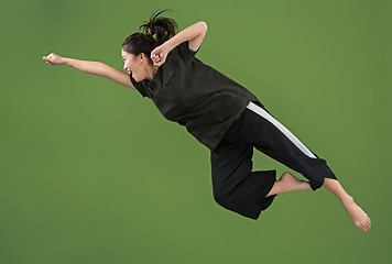 Image showing Freedom in moving. Pretty young woman jumping against green background