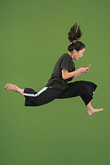 Image showing Freedom in moving. Pretty young woman jumping against green background