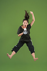 Image showing Beautiful young woman jumping with megaphone isolated over green background