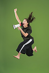 Image showing Beautiful young woman jumping with megaphone isolated over green background