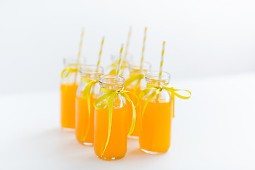 Image showing orange juice in glass bottles with paper straws