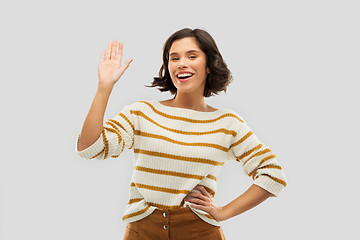 Image showing smiling woman in striped pullover waving hand