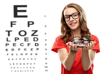 Image showing teenage girl holding glasses over eye test chart