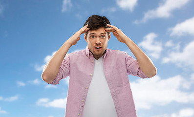 Image showing man touching his head over blue sky background