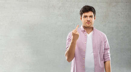 Image showing man showing middle finger over grey concrete wall