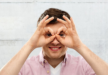 Image showing young man looking through finger glasses