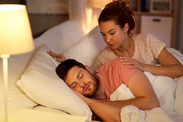 Image showing woman wakes her sleeping husband up in bed at home