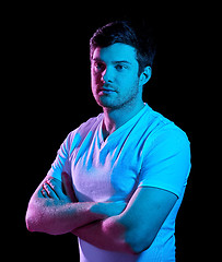 Image showing man with crossed arms over neon lights in darkness