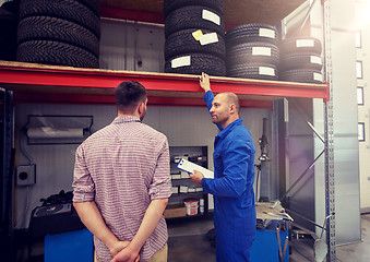Image showing auto mechanic and man with tires at car shop
