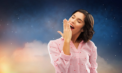 Image showing sleepy woman in pajama yawning over night sky