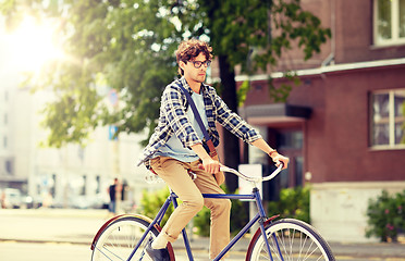 Image showing young hipster man with bag riding fixed gear bike