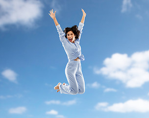 Image showing happy woman in pajama jumping over blue sky