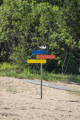 Image showing Colorful wooden signpost of directions on a sand beach.