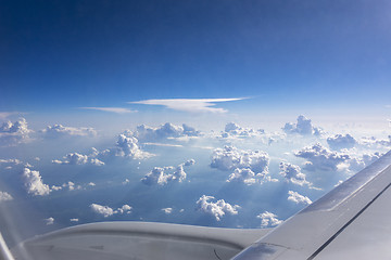 Image showing Airplane wing above fluffy white clouds in a blue sky.