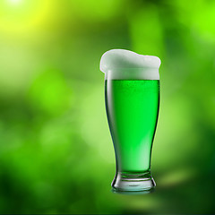 Image showing Glass of green beer on a blurred natural background.