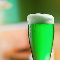 Image showing Glass of light green beer with thick foam.