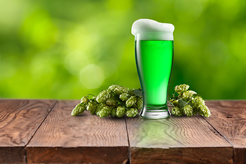 Image showing Still life with glass of fresh green beer and hops.