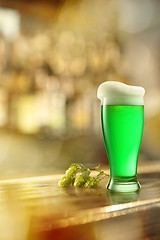 Image showing Glass of fresh green beer on a table in a bar.