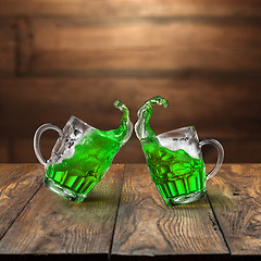 Image showing Fresh green beer splashes from two flying beer mugs.