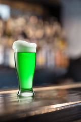 Image showing Glass of light green beer on a background of pub.